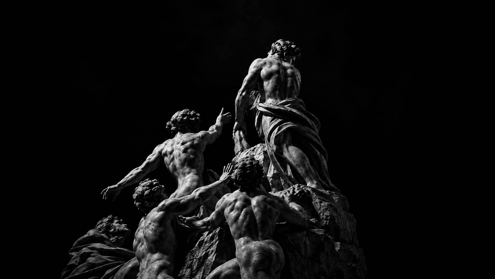 A group of sculpted figures climbing toward a standing figure on a rocky peak.
